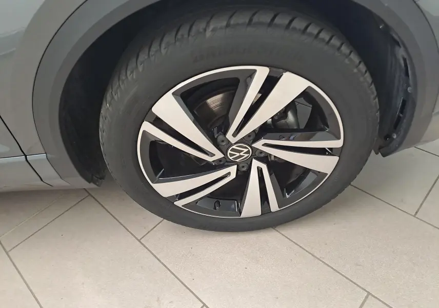 Gros plan sur la roue avant gauche du Volkswagen T-Roc gris Indium avec jante alliage bicolore distinctive.