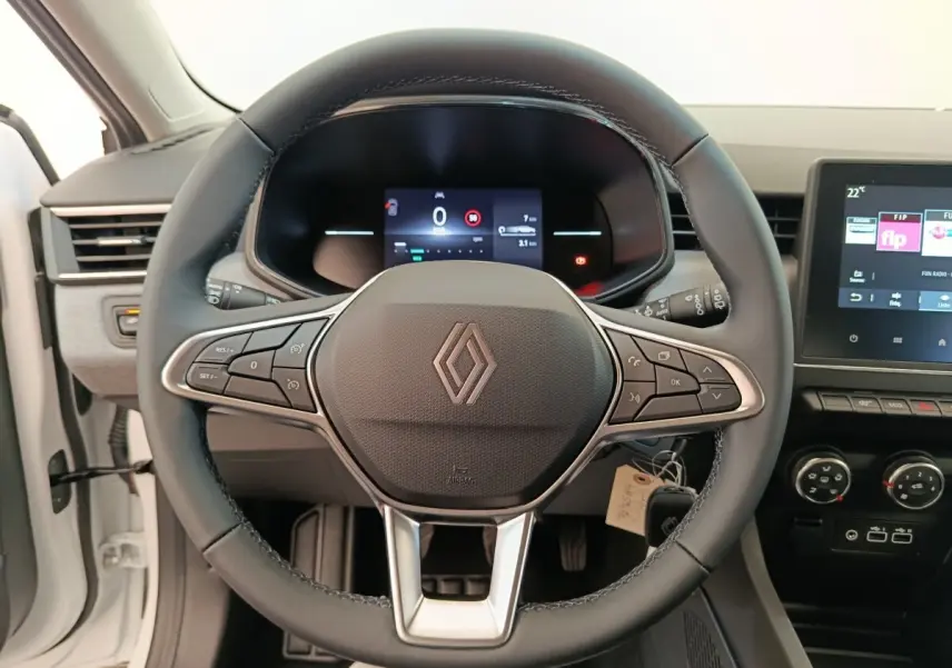 Vue intérieure centrée sur le volant cuir noir de la Renault Clio blanc 2024 avec tableau de bord digital et écran tactile.
