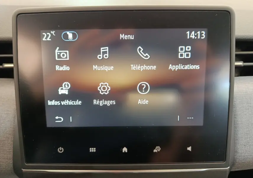 Écran tactile central de la Renault Clio 2024 affichant le menu principal avec icônes blanches sur fond sombre.