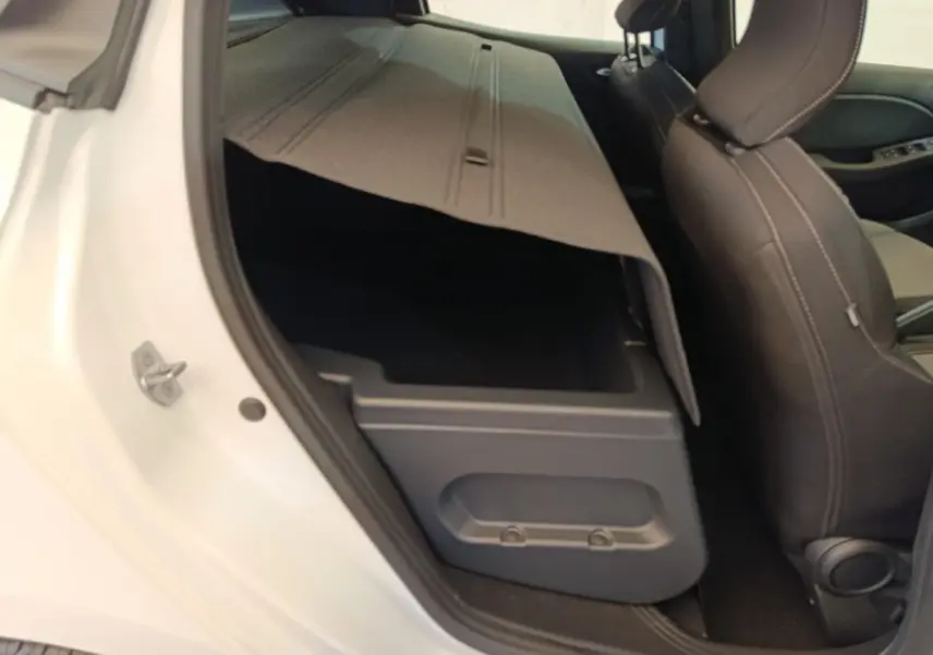 Vue intérieure côté gauche arrière d’une Renault Clio blanche 2024 montrant le coffre sous le siège arrière relevé.