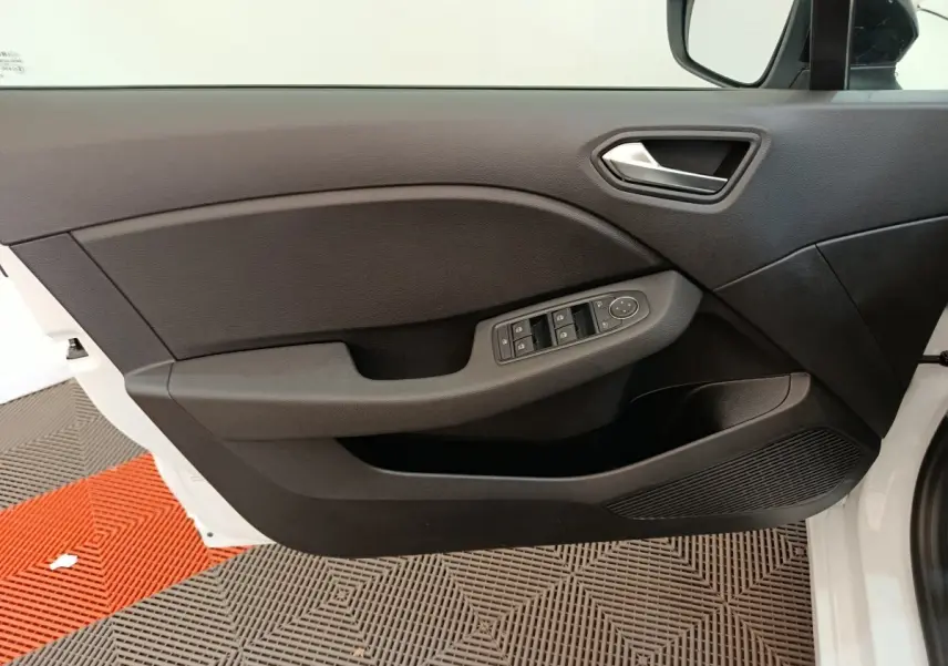 Vue intérieure de la porte avant gauche noire de la Renault Clio blanche 2024 avec commandes électriques des vitres.