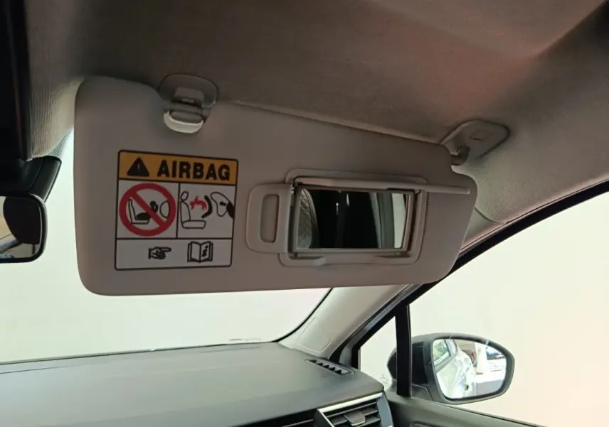 Vue intérieure côté passager de la Renault Clio blanche 2024, pare-soleil avec miroir et avertissement airbag visible.