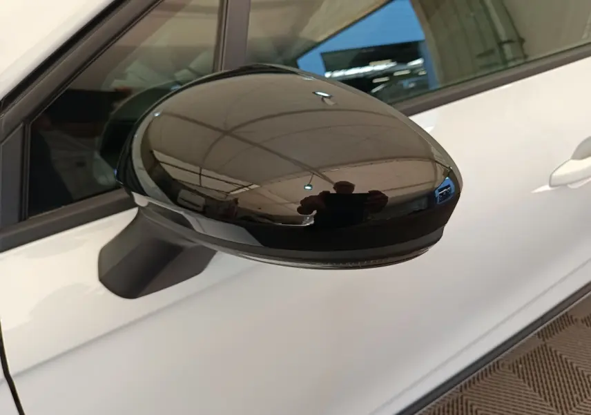 Rétroviseur noir côté gauche d’une Renault Clio blanche 2024, vue rapprochée sur la portière avant.