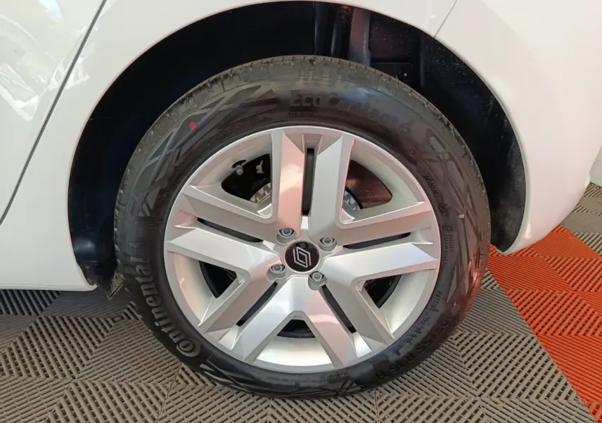 Gros plan sur la roue avant droite d'une Renault Clio blanche, mettant en valeur la jante alliage argentée et le pneu Continental.