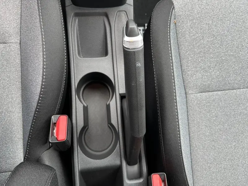 Vue rapprochée de la console centrale grise du Renault Clio 2025, avec frein à main manuel et porte-gobelets.