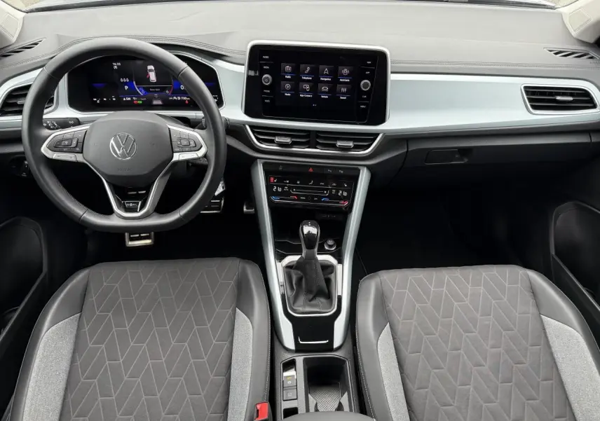Vue intérieure frontale du Volkswagen T-Roc 2025, tableau de bord moderne avec écran tactile et volant multifonction noir.