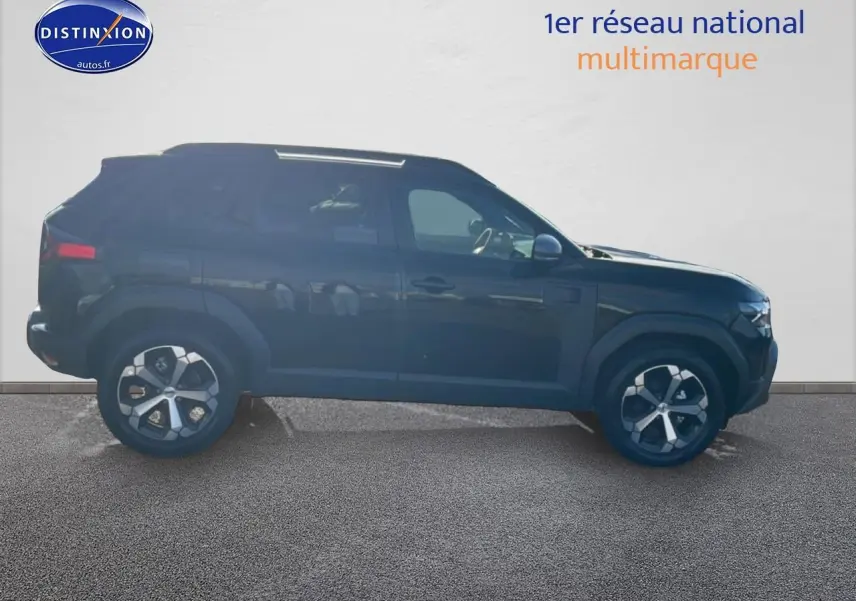 Profil côté gauche du Dacia Duster 1.2 mild hybrid noir 2026 avec jantes alu et barres de toit visibles.