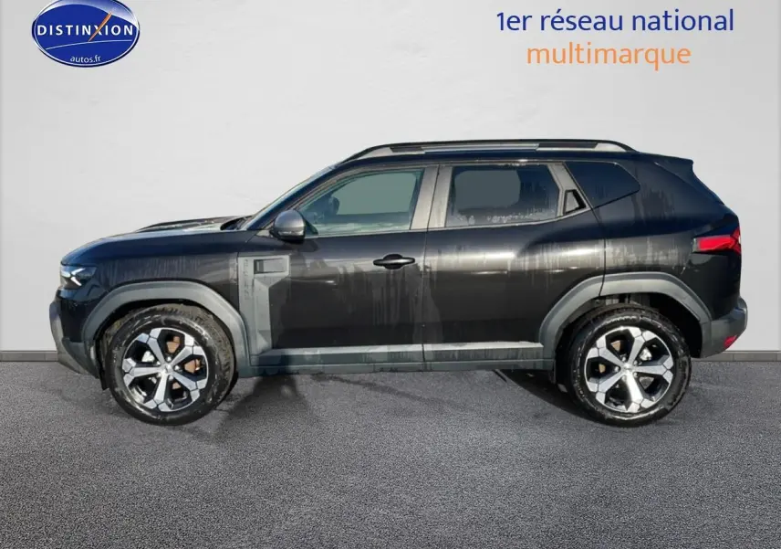 Vue de profil côté gauche d'un Dacia Duster noir 2026 avec jantes alu et barres de toit visibles.