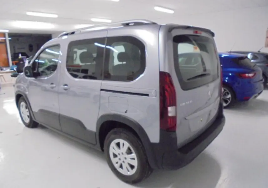 Peugeot Rifter gris Artense vu en 3/4 arrière droit, avec portes coulissantes et protections noires sur les bas de caisse.