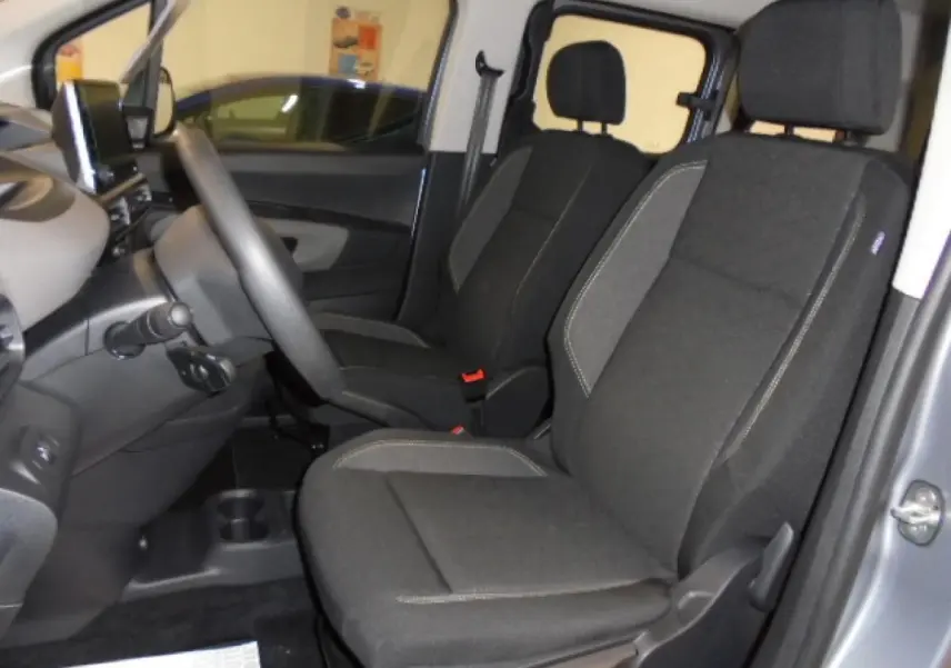 Vue intérieure côté gauche du Peugeot Rifter 2020 gris Artense, montrant les sièges avant en tissu noir avec surpiqûres grises.