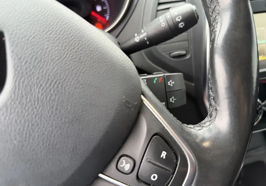 Gros plan sur le volant en cuir noir du Renault Captur TCE 120 EDC Intens, avec commandes audio intégrées.