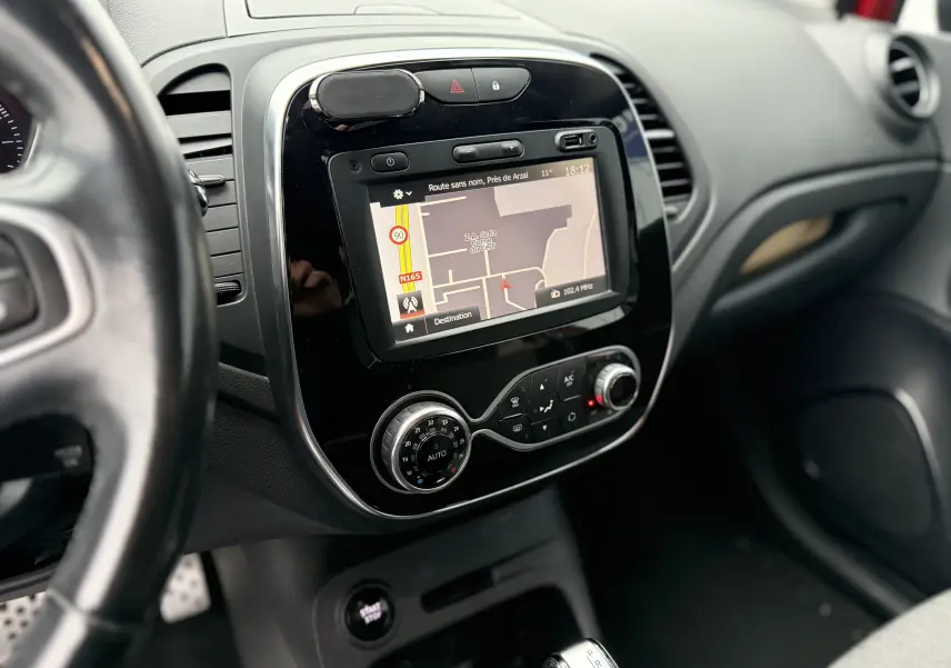 Vue intérieure rapprochée du tableau de bord du Renault Captur rouge de 2017, mettant en valeur l’écran tactile de navigation.