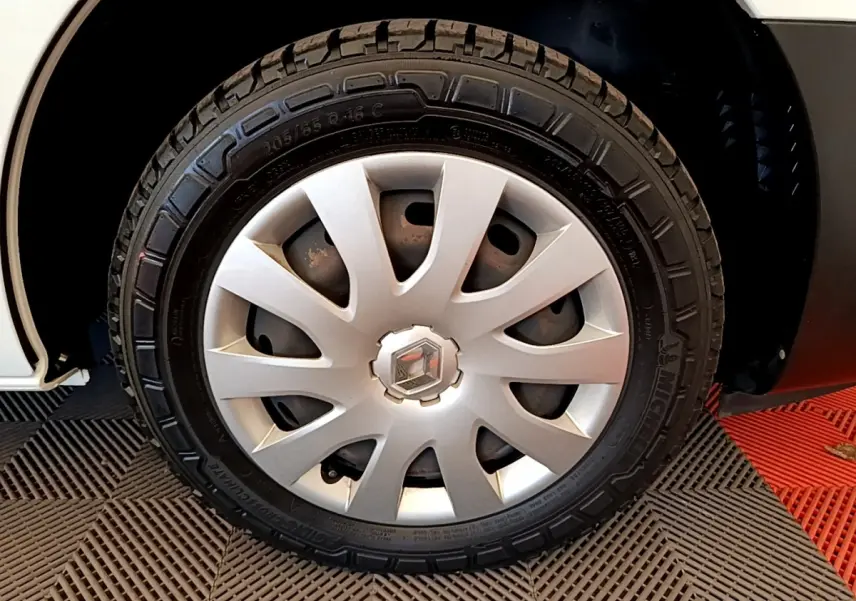 Gros plan sur la roue avant droite d’un Renault Trafic blanc, avec jante en alliage et logo Renault au centre.