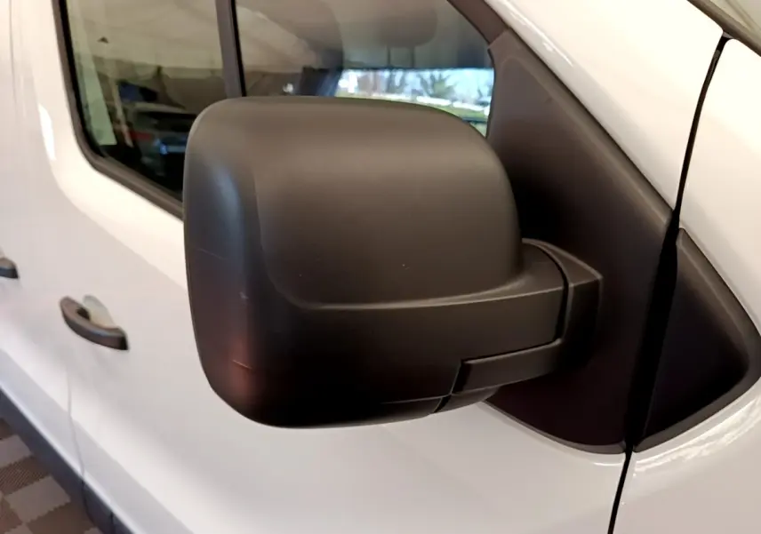 Gros plan sur le rétroviseur droit noir du Renault Trafic Fourgon blanc, vue latérale côté passager.