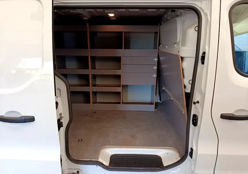 Vue intérieure côté droit du Renault Trafic Fourgon blanc 2021, montrant l'espace de chargement avec étagères intégrées.