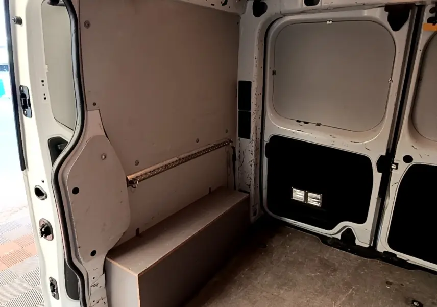Intérieur du fourgon Renault Trafic L1H1 blanc, vue de l'espace de chargement avec parois et porte arrière ouvertes.