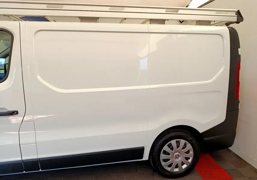 Vue latérale droite d’un Renault Trafic Fourgon blanc L1H1 2021 avec jante argentée et galerie de toit.
