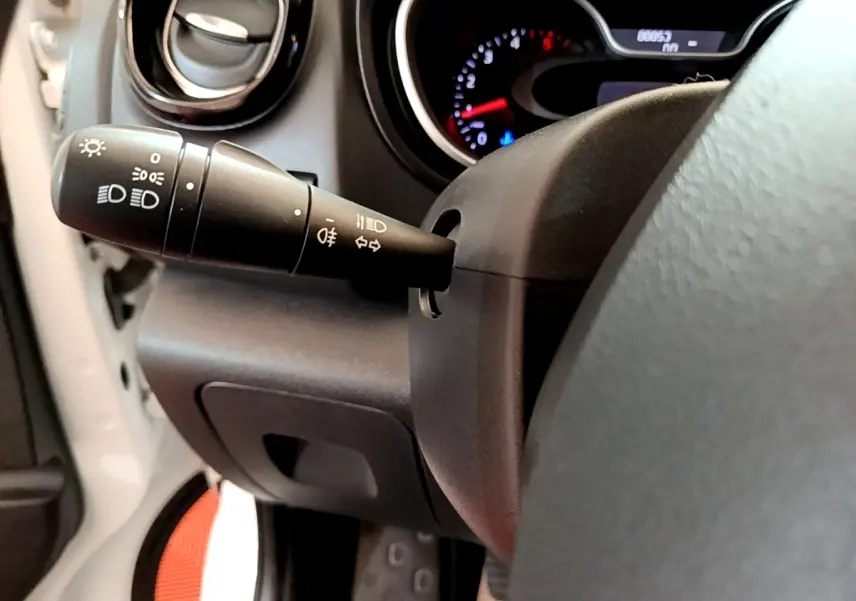 Gros plan sur la commande des feux et clignotants à gauche du volant dans l'habitacle du Renault Trafic blanc.