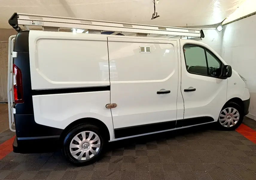 Vue latérale droite d'un Renault Trafic Fourgon blanc L1H1 1200 Confort avec galerie de toit en intérieur.