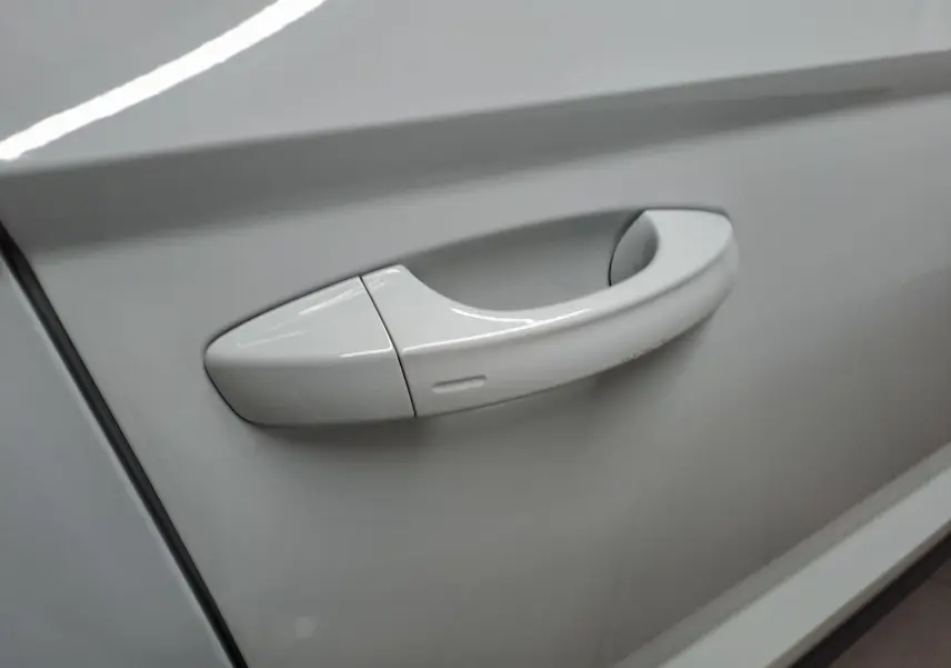 Poignée de porte blanche Lune en gros plan sur la portière d'un Skoda Karoq 2025 avec finition chromée.