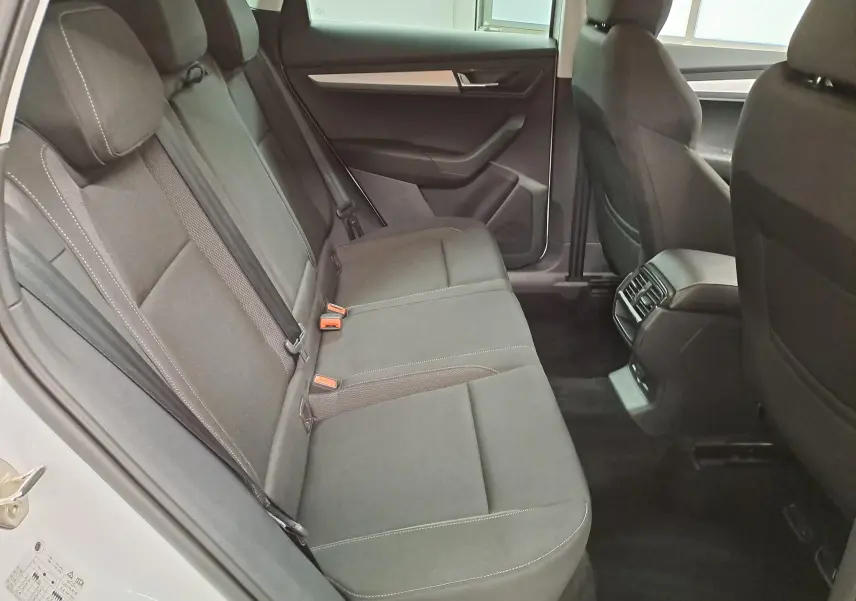 Vue intérieure arrière droite du Skoda Karoq blanc Lune 2025, sièges tissu gris avec surpiqûres contrastées.