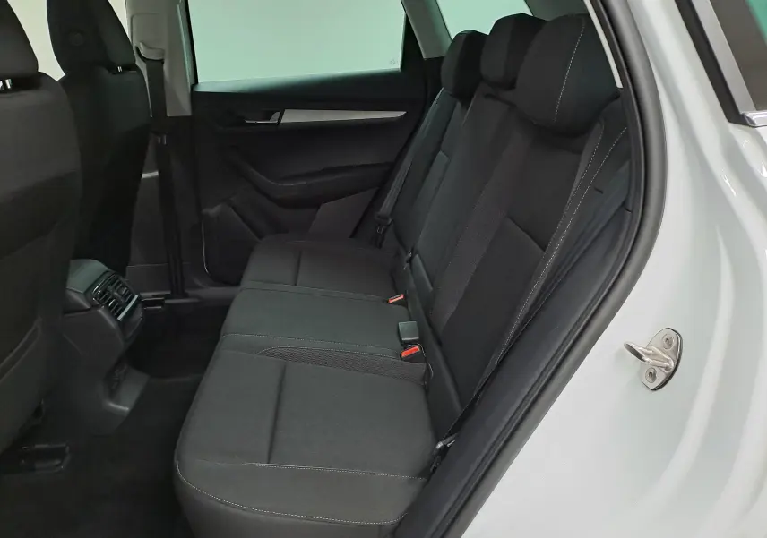 Vue intérieure côté droit des sièges arrière noirs du Skoda Karoq blanc Lune, avec porte ouverte et habillage sobre.