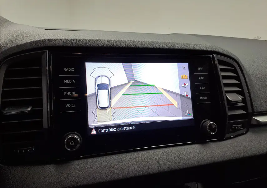 Écran central du Skoda Karoq blanc Lune 2025 affichant la caméra de recul avec repères de distance colorés.