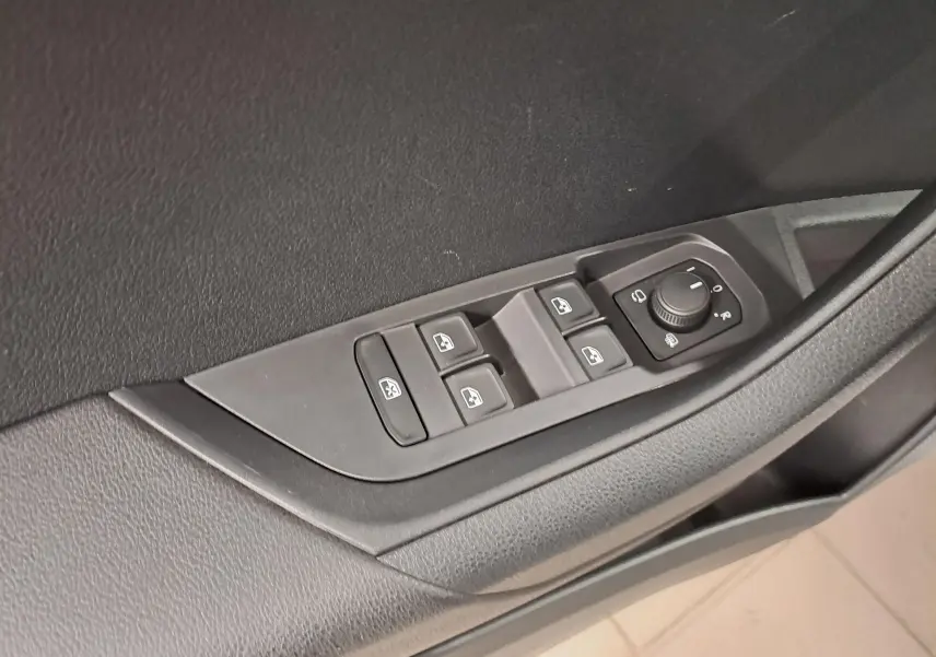 Commande des vitres et réglage des rétroviseurs sur la porte intérieure côté conducteur d'un Skoda Karoq blanc Lune 2025.