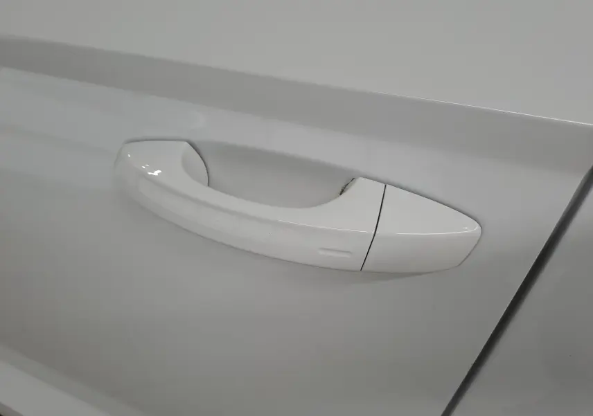 Poignée de porte blanche Lune du côté gauche d'un Skoda Karoq 1.5 TSI 150 DSG7 avec finition chromée autour des vitres.