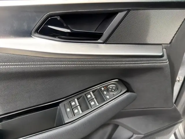 Gros plan sur la porte côté gauche du Renault Austral gris Casiopee, montrant les commandes des vitres et la poignée intérieure.