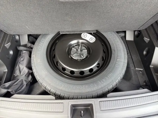 Vue rapprochée de la roue de secours temporaire noire dans le coffre du Renault Austral gris Casiopee 2025.