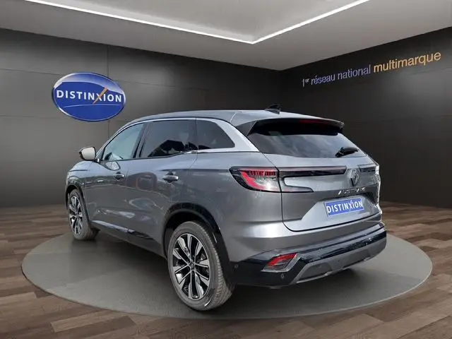 Vue 3/4 arrière droite d'un Renault Austral gris Casiopee avec jantes alliage 19'' Komah diamantées noir dans un showroom.
