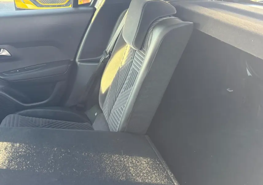 Vue intérieure côté droit sur le siège arrière gris avec détails en tissu et cuir, et partie du coffre visible.