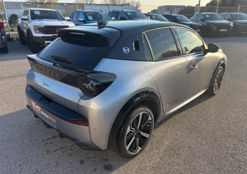 Vue 3/4 arrière droite d'une Lancia Ypsilon gris métallisé avec toit noir et jantes 17 pouces au soleil.