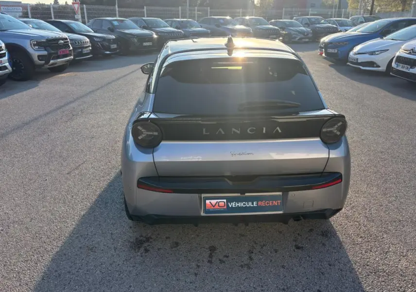Vue arrière d'une Lancia Ypsilon gris métallisé 2025, avec feux ronds et logo LANCIA bien visible.