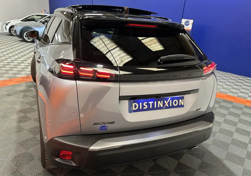 Vue 3/4 arrière droite du Peugeot 2008 gris Artense avec feux LED allumés et toit ouvrant panoramique visible.