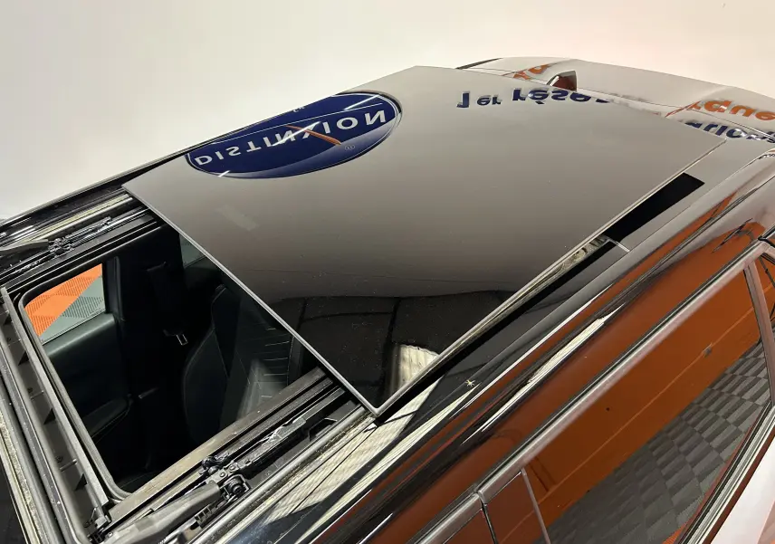 Toit ouvrant panoramique en verre noir sur Peugeot 2008 gris Artense, vue en plongée depuis l'arrière côté gauche.