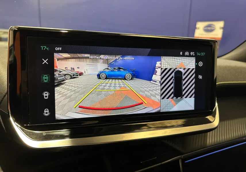 Écran multimédia montrant la caméra 360° avec vue arrière et latérale d’un véhicule bleu dans un garage.