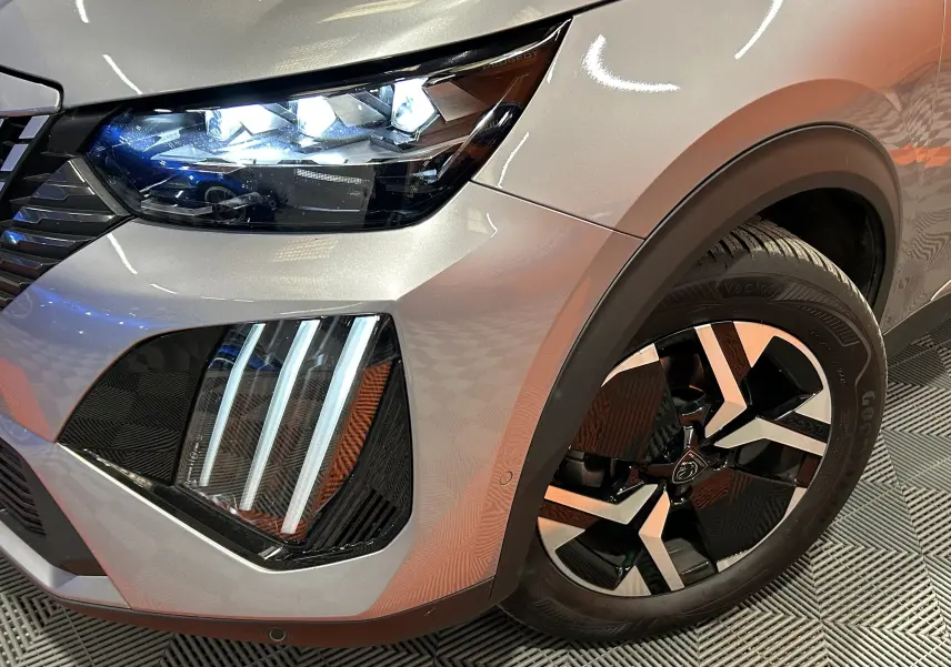 Gros plan sur l’avant droit gris Artense du Peugeot 2008 2024, mettant en valeur les phares LED et la jante noire et argent.
