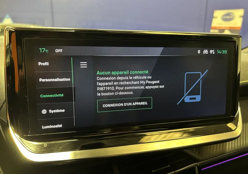 Écran tactile central du Peugeot 2008 2024 affichant le menu connectivité, avec cadre noir brillant et éclairage d’ambiance violet.