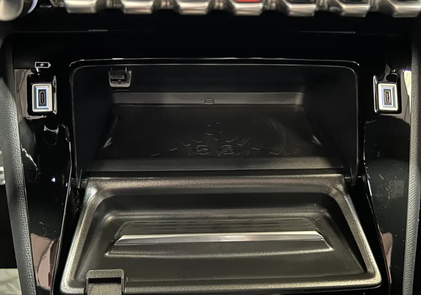 Gros plan sur la console centrale noire du Peugeot 2008 2024, montrant le compartiment de charge sans fil et deux ports USB-C.