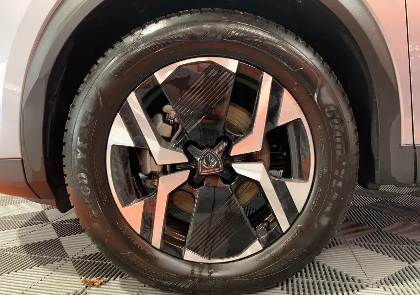 Gros plan sur la jante avant droite du Peugeot 2008 gris Artense avec logo Peugeot au centre et pneu Goodyear.
