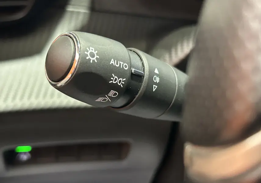 Gros plan sur la commande des phares du Peugeot 2008 gris Artense, avec réglage automatique et feux antibrouillard.