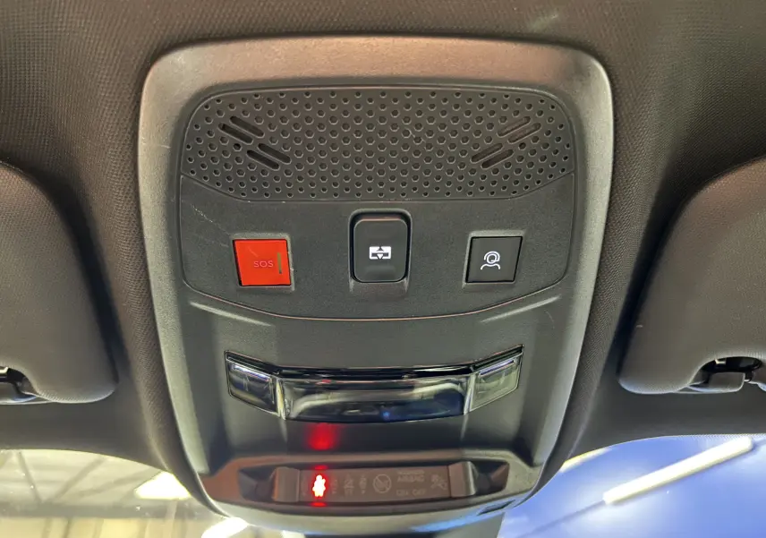 Vue en contre-plongée du panneau de commande au plafond intérieur du Peugeot 2008 gris Artense, avec bouton SOS rouge et éclairage intégré.