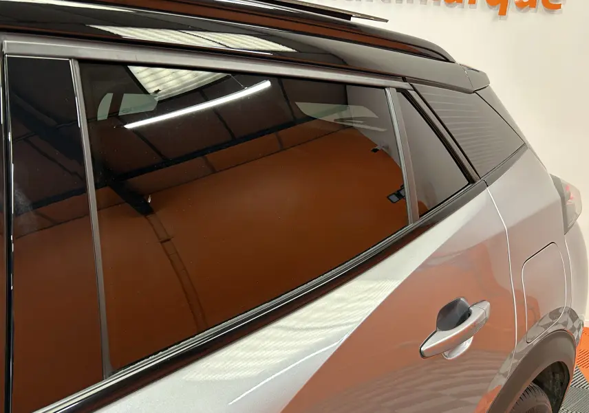 Vue rapprochée du côté arrière droit du Peugeot 2008 gris Artense avec vitres teintées et poignée de porte visible.