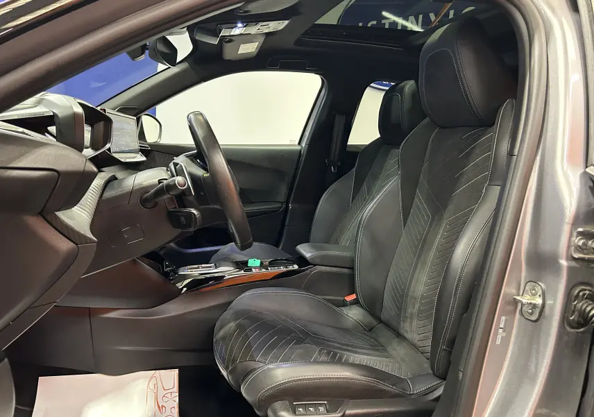 Vue intérieure côté conducteur du Peugeot 2008 gris Artense 2024, sièges cuir Alcantara avec surpiqûres et toit panoramique.