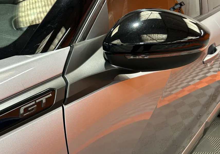 Gros plan sur le rétroviseur noir et l’emblème GT du côté gauche d’un Peugeot 2008 gris Artense.