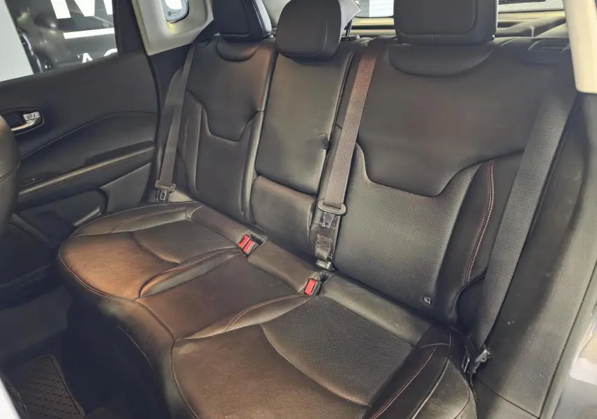 Vue intérieure montrant la banquette arrière en cuir noir du Jeep Compass Trailhawk, avec ceintures de sécurité visibles.