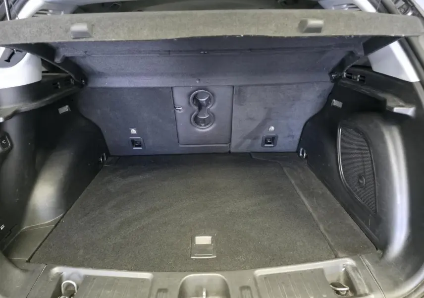 Coffre ouvert vu de l'arrière d'un Jeep Compass gris, montrant l'espace de chargement et la moquette noire.