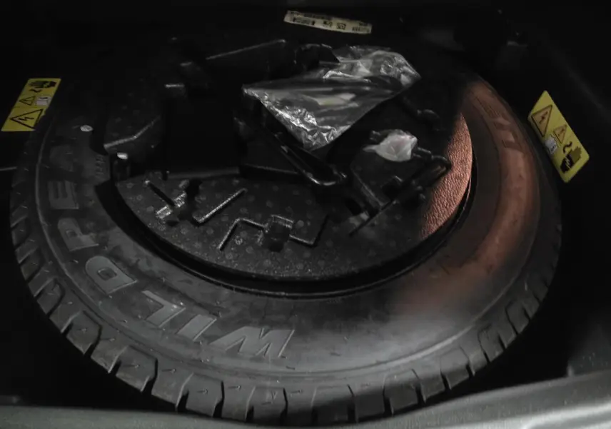 Gros plan sur la roue de secours et les outils de la Jeep Compass Trailhawk 2020, dans le coffre sombre.